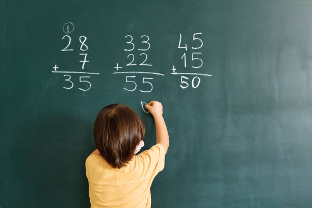 istock Cute child writing mathematics at blackboard. Back to school 1255434128