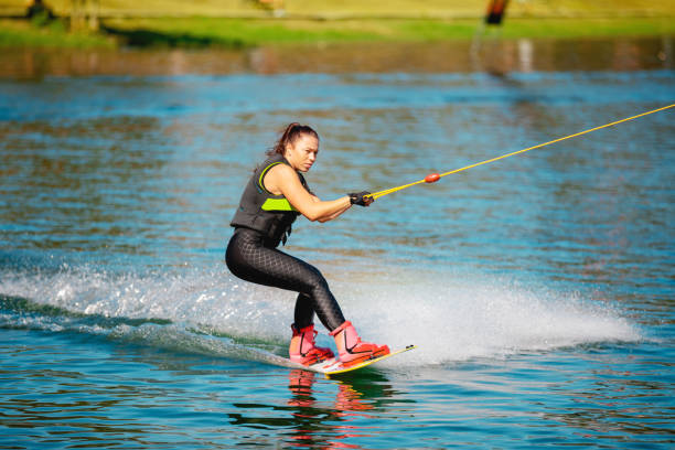 istock Young woman on wake board pulled by cable on the lake 1255434448