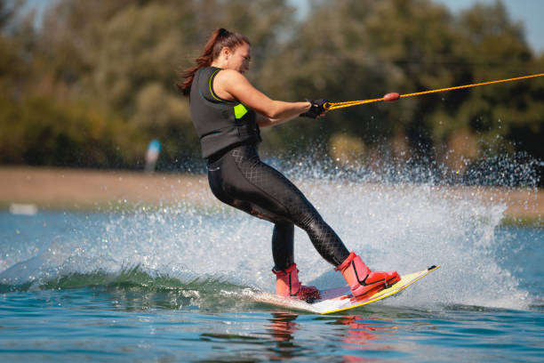 istock Young woman tilting wakeboard on the lake and splashing 1255434510