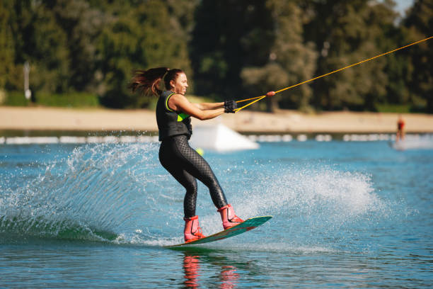 istock Young woman holding cable and lifting up wakeboard front 1255434550