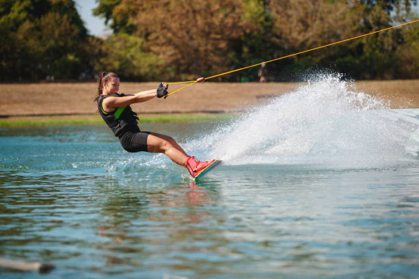 istock Young woman reclining backwards on wakeboard and splashing 1255435138