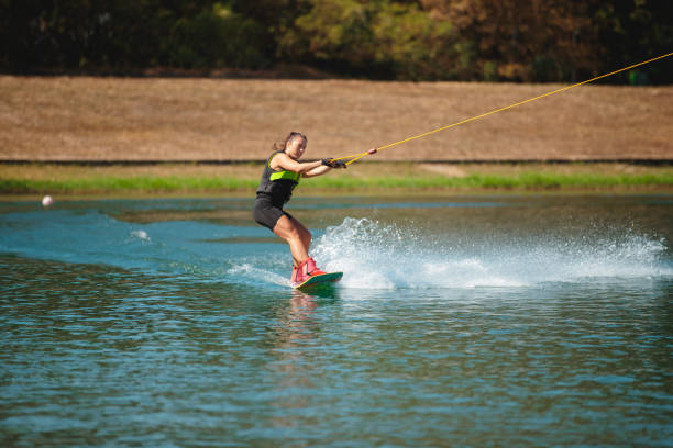 istock Young woman on wakeboard cutting lake surface 1255435145