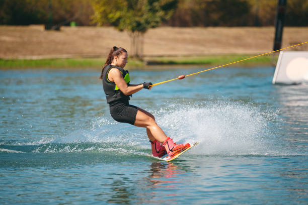 istock Young woman on wakeboard reclining backwards and splashing 1255435146