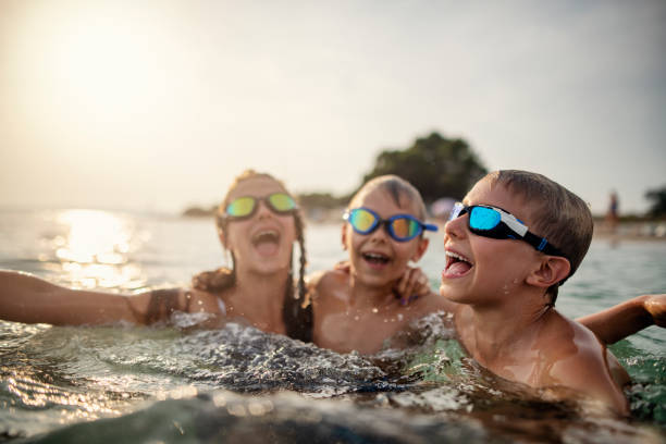istock Thee kids having fun playing in sea 1255436953