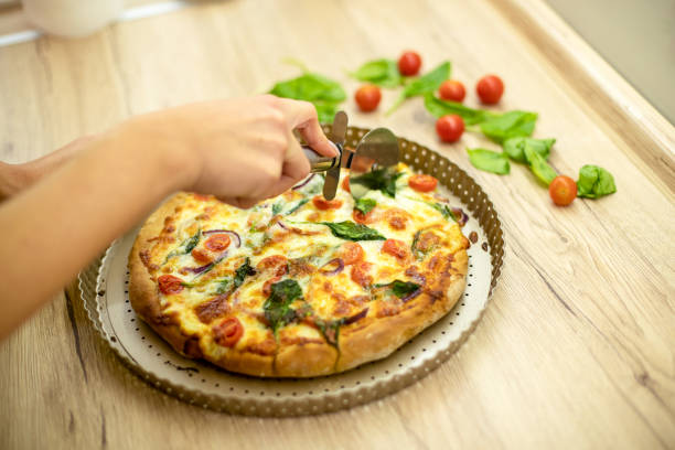 The girl cuts the pizza with a roller stock photo
