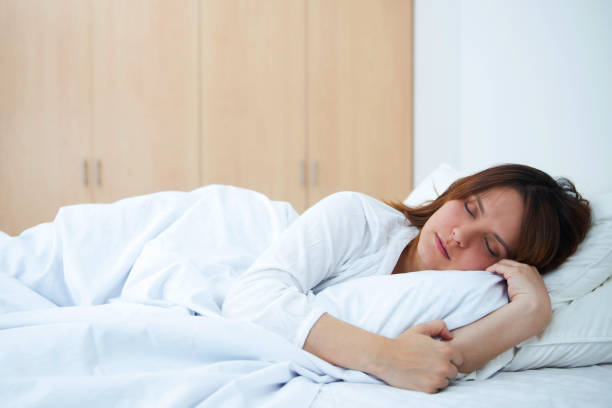 istock Young female sleeping n bed peacefully 1255442433