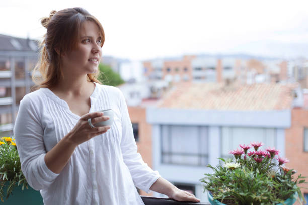 istock Beautiful young woman looking away daydreaming while enjoying a coffee 1255442466