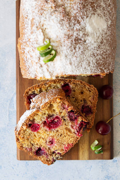 rebanadas de pastel de libra casero con cerezas y nueces en tabla de cortar madera. fondo de piedra azul claro. vista superior. - pound cake fruitcake cake loaf of bread fotografías e imágenes de stock