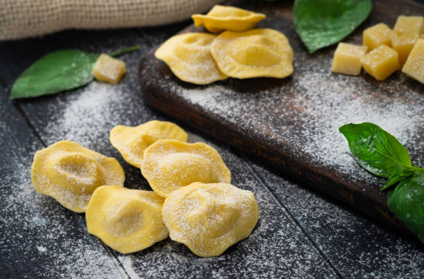 istock Fresh ravioli with cheese and Basil sprinkled with flour on wooden background on kitchen table, dark background 1255451763