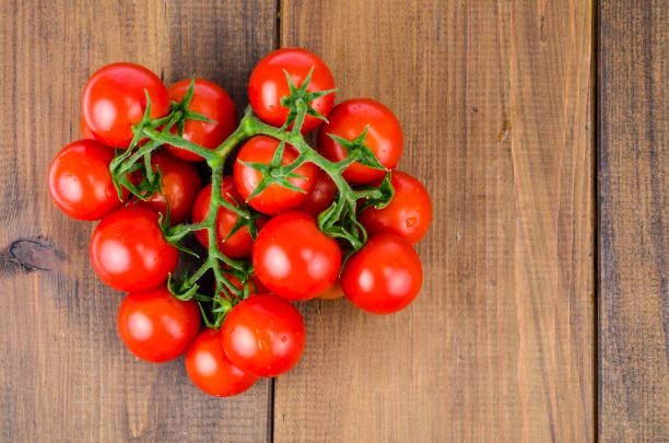 istock Bunch of red small round tomatoes on wooden background. 1255454577
