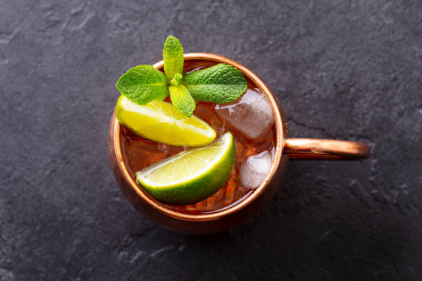 Moscow Mules cocktail with ginger beer, vodka, lime and mint. Grey background. Close up. Top view.