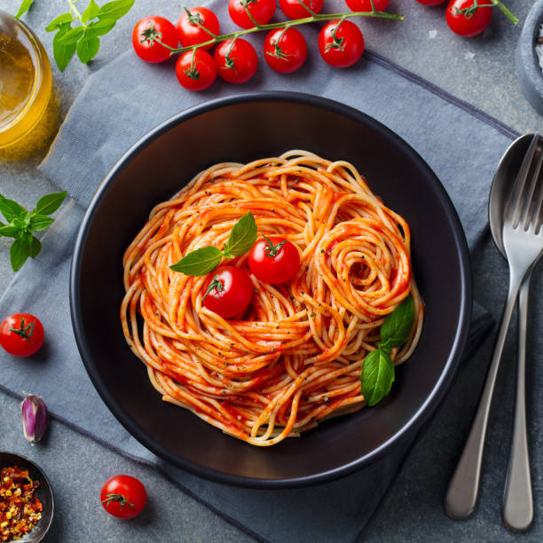 istock Pasta, spaghetti with tomato sauce in black bowl. Grey stone background. Close up. Top view. 1255459408