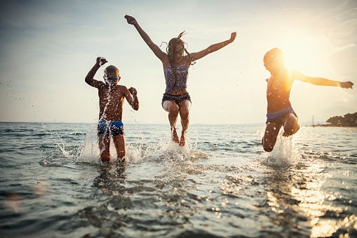 Brothers and sister are having fun in sea waves.\nSunny summer day evening.\nNikon D850