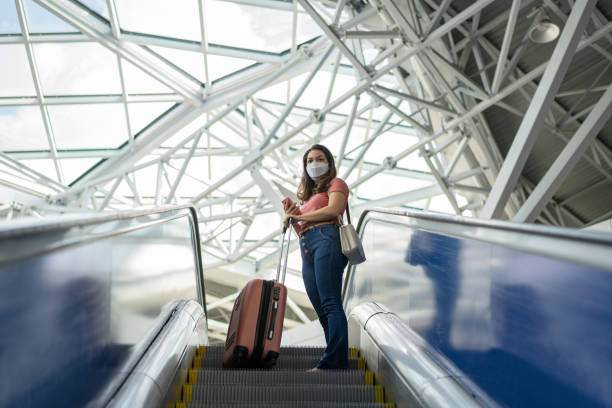 istock Woman on an escalator wearing face mask 1255461598