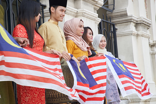 Low angle view of Malaysia multi ethnic adults holding malaysia flag celebrating their independence day at merdeka square