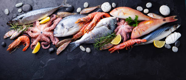Fresh fish and seafood assortment on black slate background. Copy space. Top view. Fresh fish and seafood assortment on black slate background. Copy space. Top view. shrimp seafood photos stock pictures, royalty-free photos & images