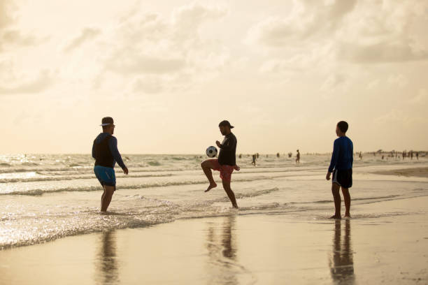 istock Three people playing soccer on the beach in Florida 1255463217