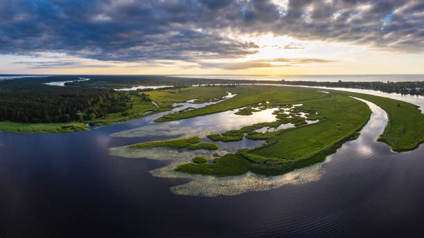 River Lielupe in summertime Panoramic view of sunset over river Lielupe by Jurmala on a summer evening. Baltic sea can be seen in distance. Lake Babite can be seen on the left side estuary stock pictures, royalty-free photos & images