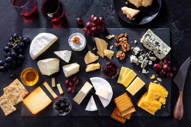 assortiment de fromage sur planche à découper d’ardoise avec vin rouge. fond gris. vue supérieure. - cheese portion cracker cheddar photos et images de collection