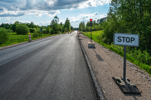 Red traffic light and a STOP sign of the road repair in section Vecpiebalga - Madona, Latvia
