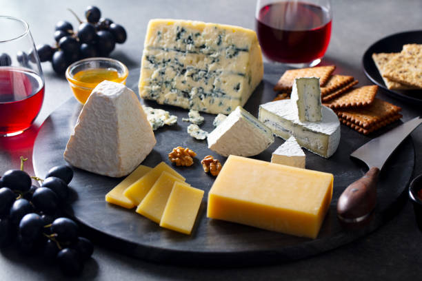 istock Cheese assortment on dark marble cutting board with red wine. Grey background. 1255465506