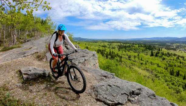 Female mountain E-biker rides down mountain ridge
