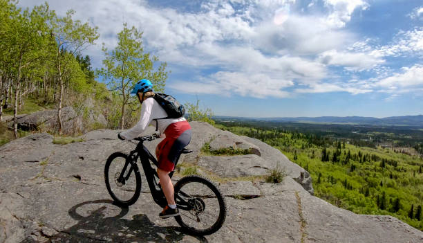 istock Female mountain E-biker rides up mountain ridge 1255466549