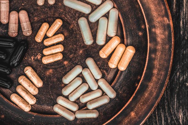 поливитаминные таблетки на глиняной тарелке, на старинном деревянном столе - lecithin стоковые фото и изображения
