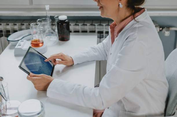 istock Women in Science: a Anonymous Senior Female Scientist in a Lab Coat Using a Digital Tablet During Research 1255469822