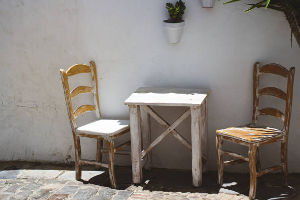 istock White rustic table and chairs on an outdoor terrace isolated in white wall. 1255469915