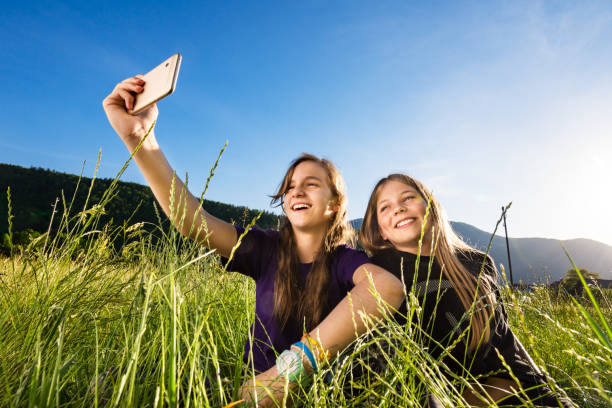 istock Two girls taking selfie in meadow using mobile phone 1255471539