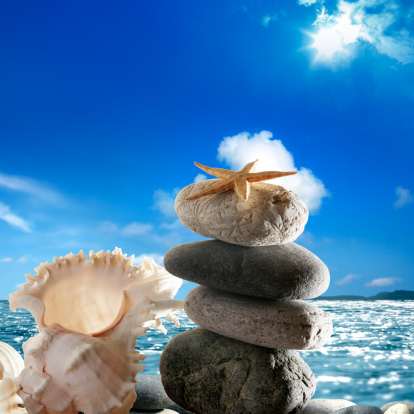 Pile of pebble Stones over blue ocean, clear sky and sunbeam.