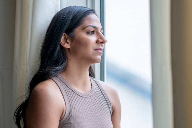 istock Young woman looking out window 1255478174