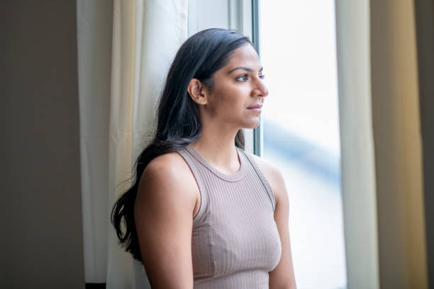 istock Young woman looking out window 1255478198