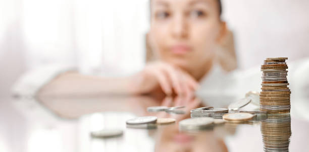 istock A woman looks thoughtfully at a fallen stack of coins on a mirrored table 1255478977