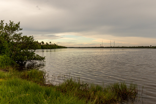 Daylight fades on the Indian River near Titusville, Florida, with Kennedy Space Center launch towers visible in the background.