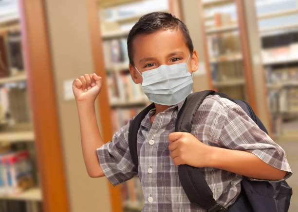 istock Hispanic Student Boy Wearing Face Mask with Backpack in the Library 1255481225