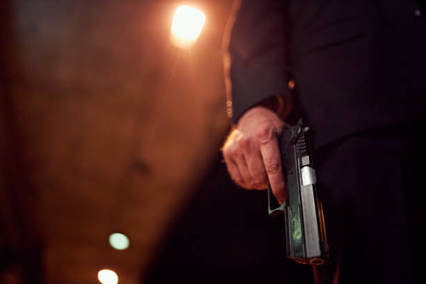 Unrecognizable person holding a handgun at night Mysterious unrecognizable man carrying a gun at night. assassination photos stock pictures, royalty-free photos & images