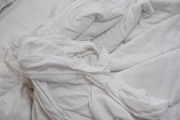 istock White delicate soft background of fabric or bedding sheet in dark room. 1255485192