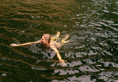 Mature active woman swimming in a small lake