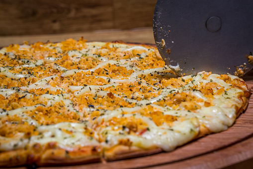 cutting the chicken pizza with Catupiry cheese, in Brazil it is called chicken pizza with catupiry cheese.
