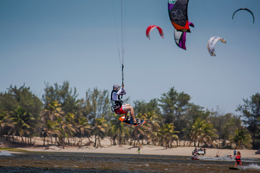 Athletic man having fun while kitesurfing on the sea. Copy space.