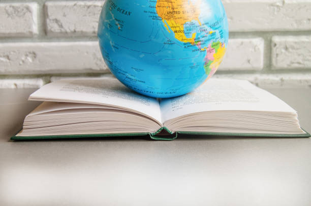 istock Happy teacher's Day, open book and globe with copy space, still life against a white brick wall 1255501077