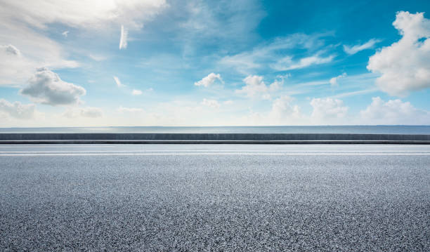 istock Asphalt road and lake water under blue sky. 1255502112