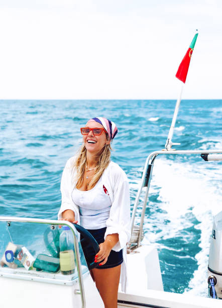 Beautiful woman is climbing ladders on a sailboat, getting out of the sea. The sea is beautiful turquoise color.