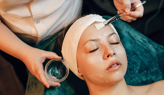 Anti aging facial mask applied to a caucasian woman in a wellness spa center using a special brush