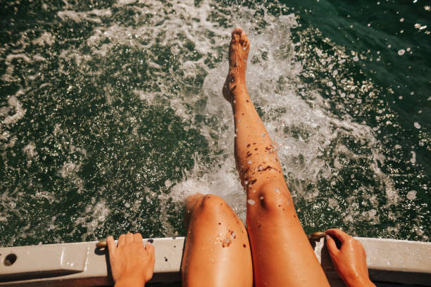 jeune femme s’asseyant sur un bateau et éclaboussant sur l’eau - sea swimming greece women photos et images de collection