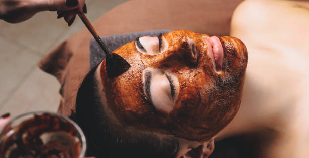 kaukaska kobieta o zabiegu pielęgnacji twarzy z maską kakaowca stosowane w salonie spa - rebellion aging process facial mask beauty treatment zdjęcia i obrazy z banku zdjęć