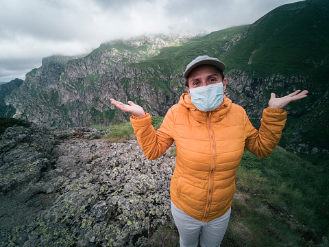A cheerful adult tourist relaxing in the Nature. Casual Clothing. Weekend Activities. Woman hiking in the highlands at the end of the quarantine of COVID-19.