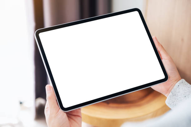 istock a woman holding black tablet pc with blank desktop white screen while sitting on a cozy white bed at home 1255521231